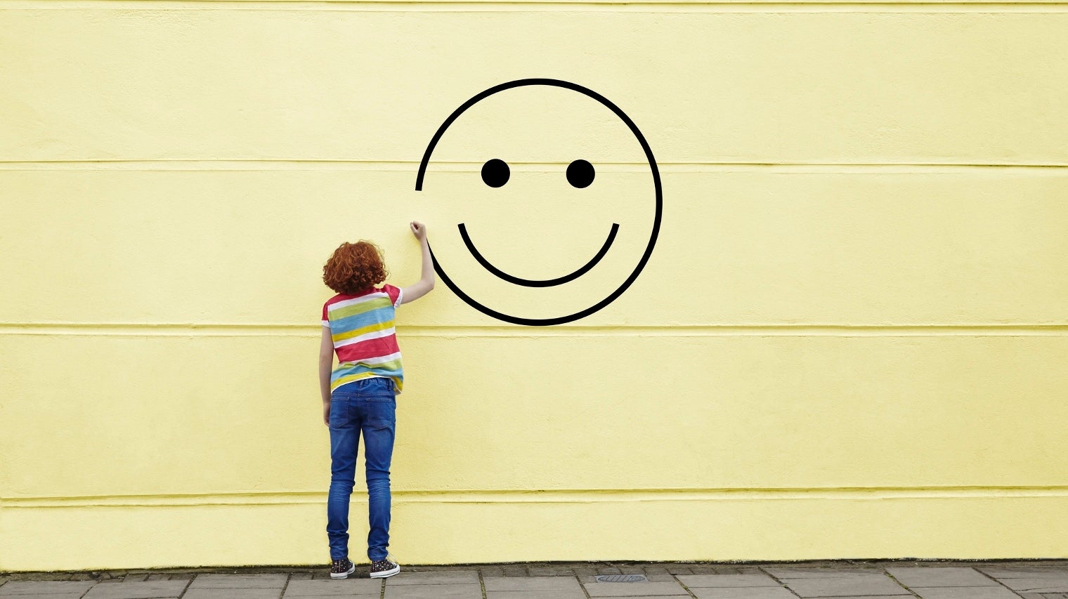 Girl drawing smiley face on to a wall