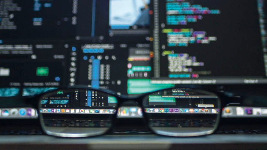 chief data officer glasses in front of laptop screen covered in text