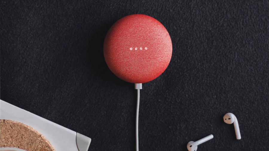 digital assistant plugged in on a dark surface next to cordless headphones