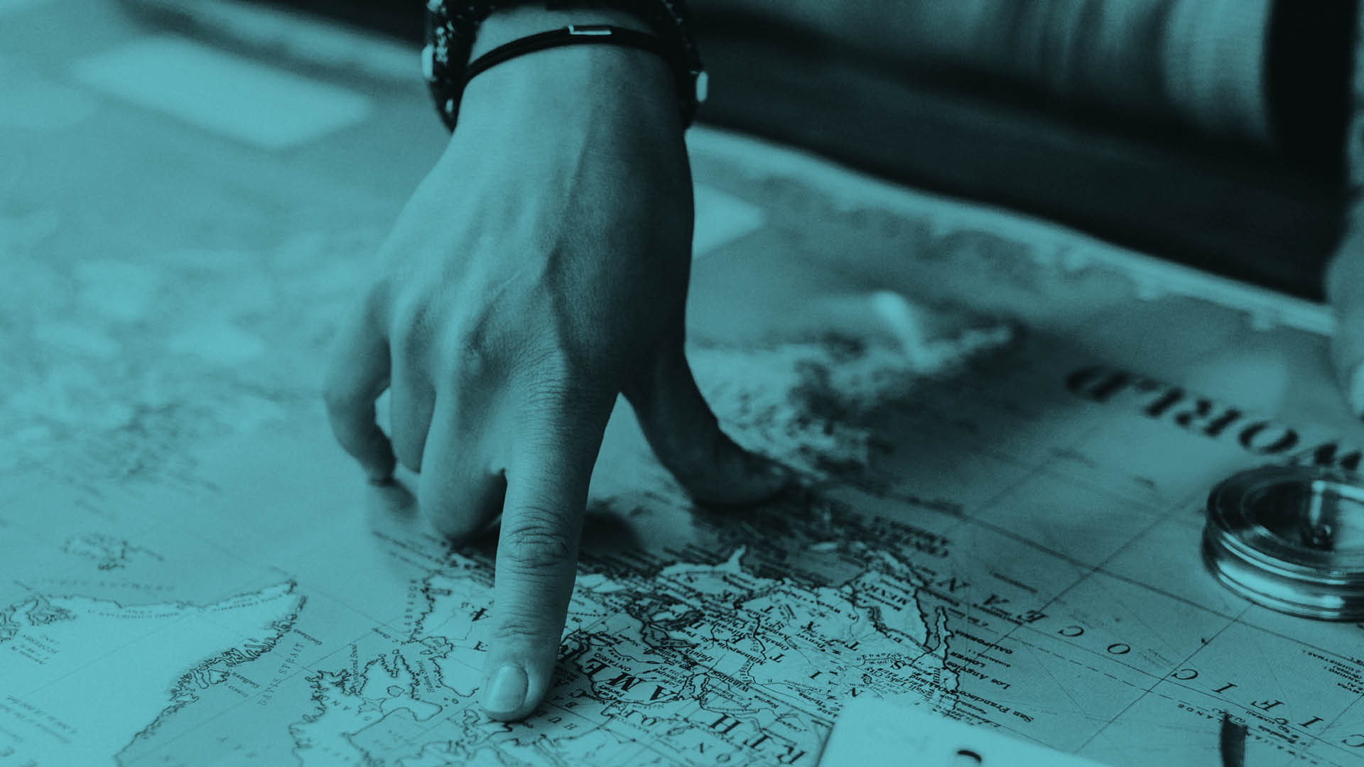 Finger pointing to map, green-blue overlay