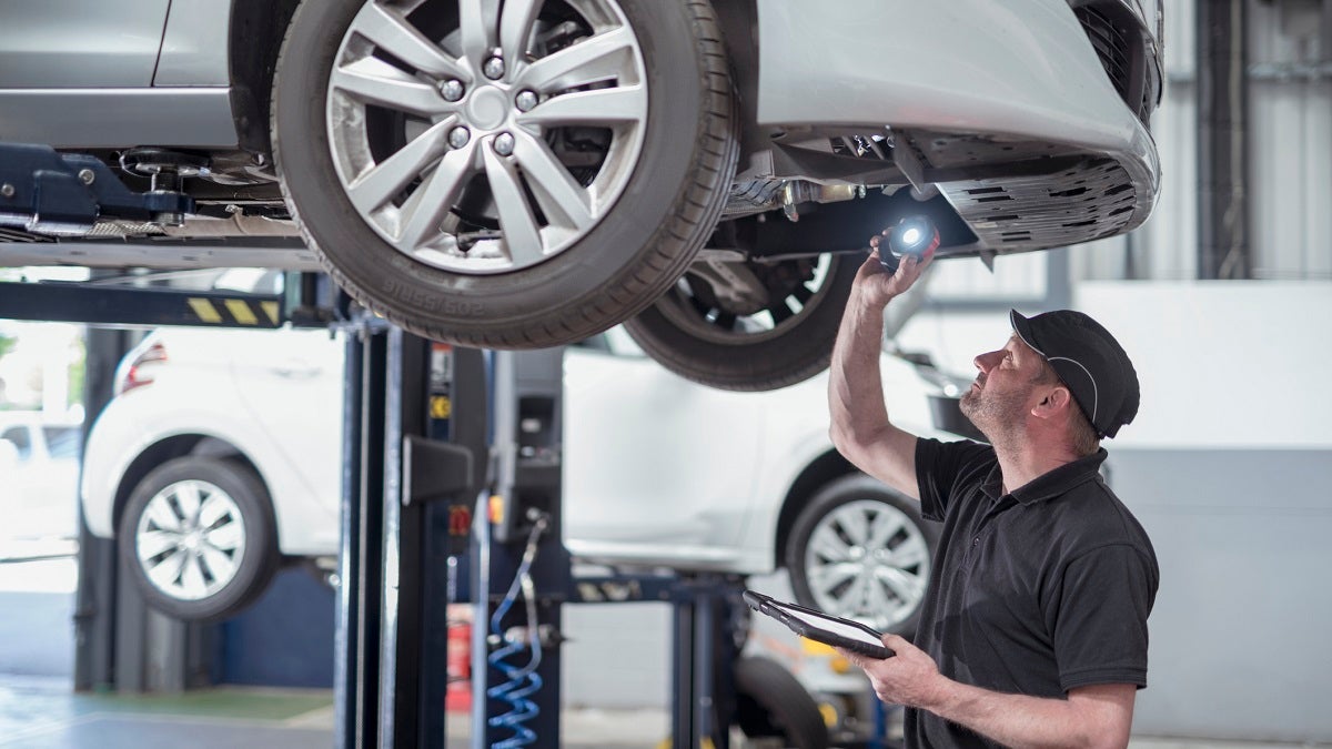 Engineer checking car on ramp in car service centre