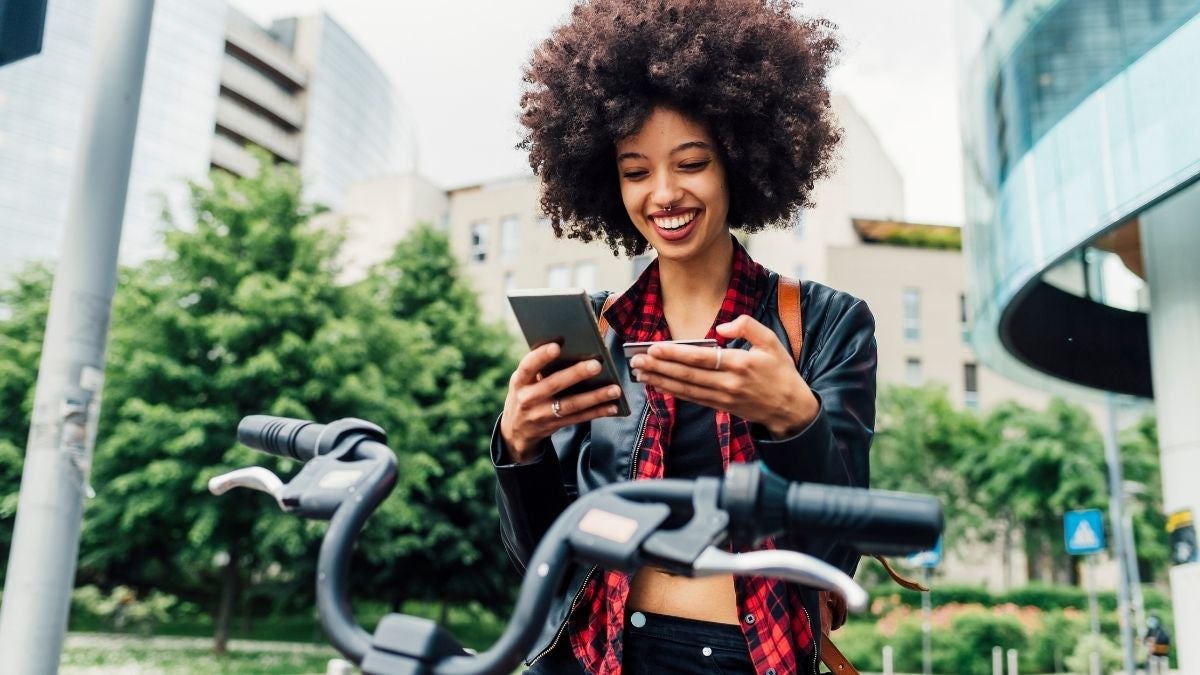 Young woman checks banking app while on the move 