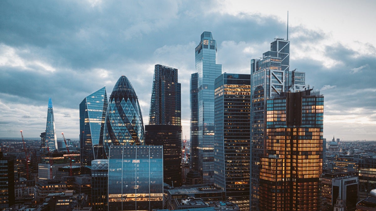 Aerial panoramic view of The City of London cityscape skyline with metropole financial district modern skyscrapers after sunset on night with illuminated buildings and cloudy sky in London, UK