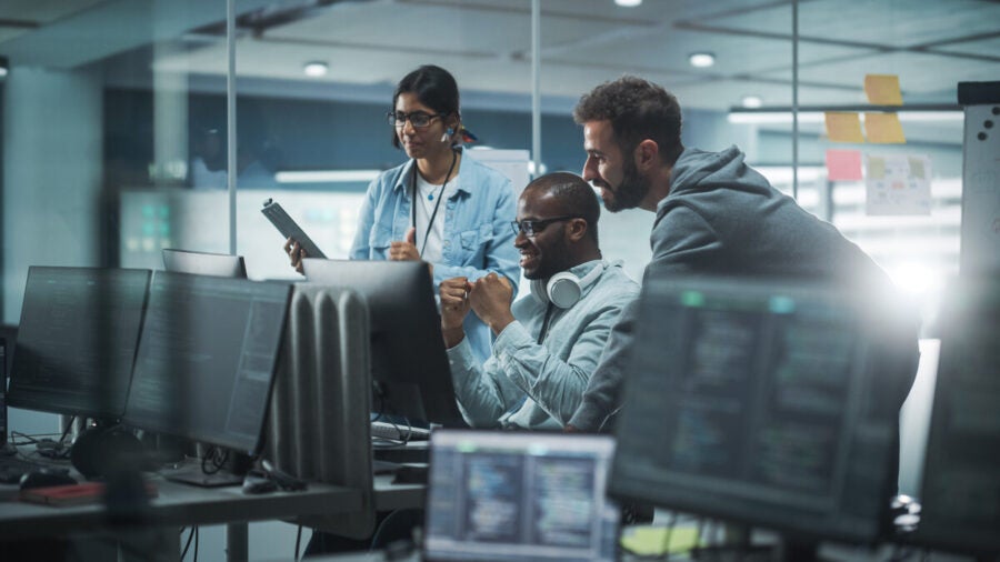 Diverse Group Of Professionals Meeting In Modern Office: Brainstorming It Programmers Use Computer Together, Talk Strategy, Discuss Planning. Software Engineers Develop Inspirational App Program
