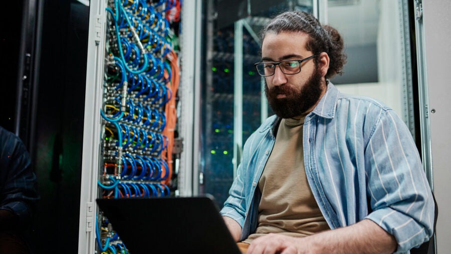 IT expert working on a laptop in a server room