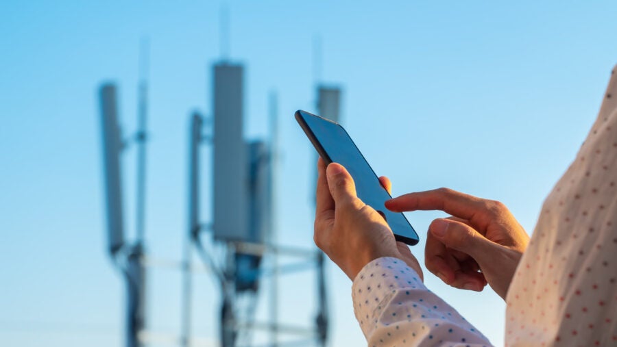 5g Communications Tower With Man Using Mobile Phone