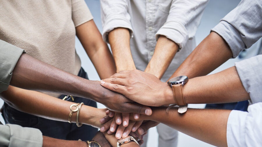 High Angle Shot Of A Group Of Unrecognisable Businesspeople Joining Their Hands Together In A Huddle