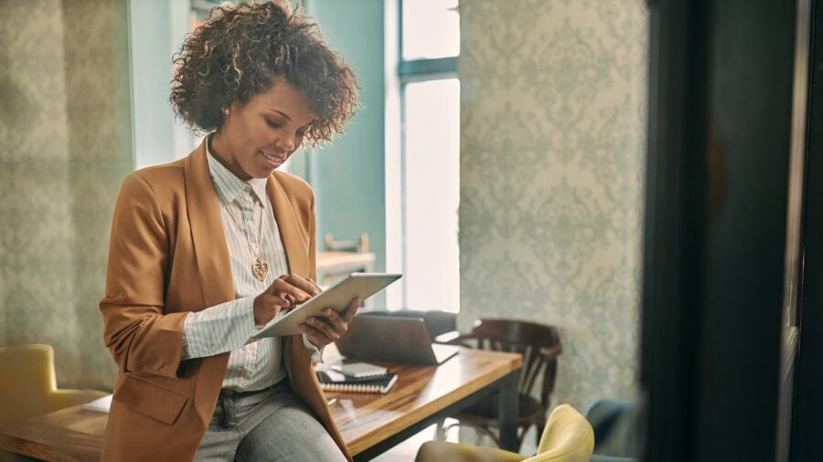 Businesswoman sitting on the desk in the office and using digital tablet