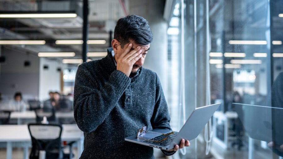 Worried Mature Man Using Laptop Working At Office